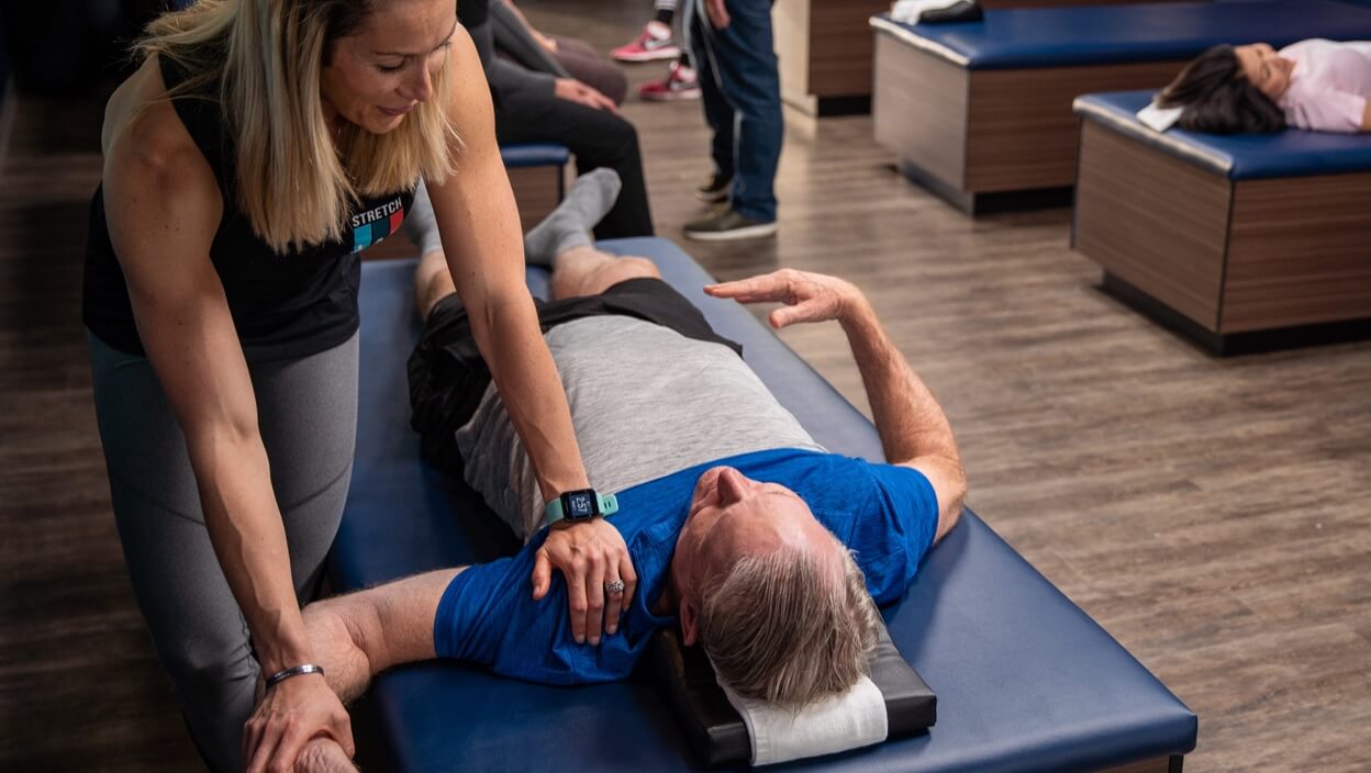 StretchLab instructor assisting person with stretch