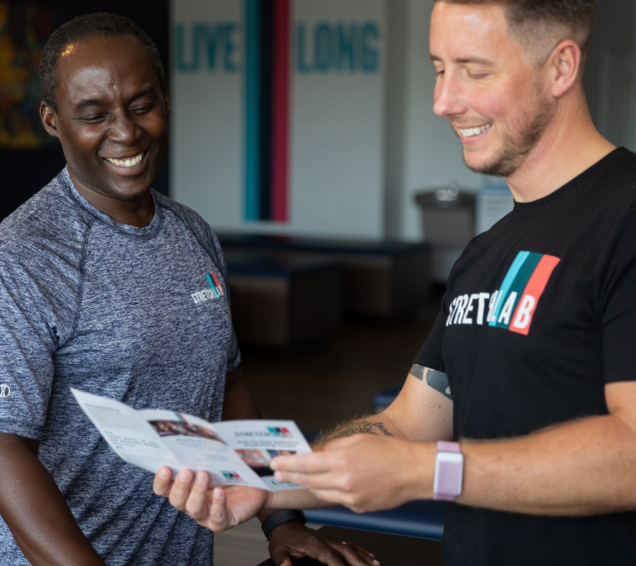 Two people looking at StretchLab pamphlet